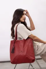Bolso tipo shopper color rojo, confeccionado en 100% cuero vacuno, con diseño geométrico de paneles y detalle de fleco decorativo colgante.