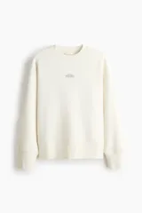 Buzo de corte holgado color blanco con cuello redondo acanalado, hombros caídos y diseño estampado en el pecho con la frase 'Note Floreat'. Cuenta con puños y bajo acanalados anchos.