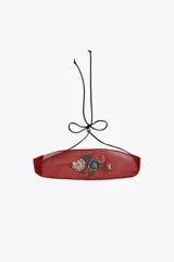 Choker de tela semitransparente color bordó con bordado floral multicolor en el centro y cierre mediante lazada ajustable con cordón negro.