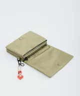 Bandolera de diseño rectangular en color verde oliva, con solapa frontal y logo de la marca grabado. Incluye una correa larga ajustable con el nombre de la marca tejido y un charm decorativo con forma de corazón y letra R en color rojo.