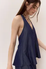 Blusa azul de denim liviano, con escote en V y cuello halter. Cuenta con cierre frontal de botones y diseño suelto de caída fluida.