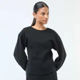 Buzo de cuello redondo negro, con mangas largas abullonadas y costuras frontales marcadas.