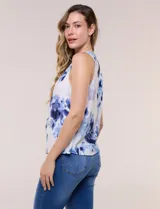 Blusa sin mangas de viscosa blanca con estampado floral en tonos azules, cuello redondo y cierre frontal parcial con botones.
