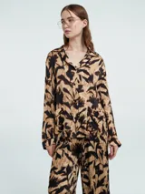 Camisa de manga larga con estampado abstracto en tonos beige y negro, con botones delanteros y bolsillos en el pecho.