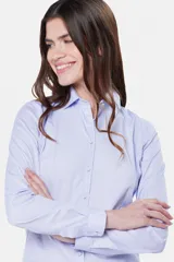 Camisa celeste de corte clásico, con cuello camisero, mangas largas con puños abotonados y cierre frontal con botones.