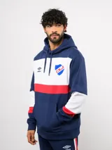 Canguro con capucha de Umbro del Club Nacional de Football, con diseño de bloques de color en azul, blanco y rojo. Presenta bolsillo frontal tipo canguro, cordones ajustables en la capucha y logos bordados del club y la marca.