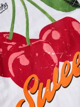 Remera de cuello redondo y mangas cortas, con calce holgado y estampa frontal de cerezas con texto decorativo.