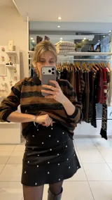 Falda corta de gabardina elastizada color negro, con diseño de tachas metálicas plateadas distribuidas por toda la prenda.