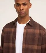 Camisa de manga larga con diseño de cuadros en tonos marrones, confeccionada en algodón. Presenta cuello camisero, cierre frontal con botones y un bolsillo en el pecho con botón.