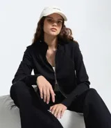 Saco negro de modal con recortes modernos y cierre delantero por cremallera. Tiene cuello alto y mangas largas.