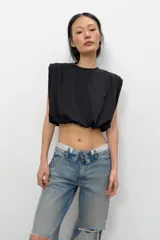Top de algodón con cuello redondo, diseño sin mangas con hombreras marcadas y detalle de pliegues. Presenta un bajo acabado tipo globo con elástico.
