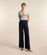 Blusa de manga corta confeccionada en tejido de viscosa texturizado, con escote en V profundo que presenta un detalle de aro metálico central.