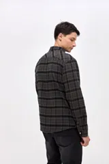 Camisa de corte regular fit, confeccionada en tela de algodón con diseño de cuadros en tonos marrones y negros. Presenta cuello clásico, cierre frontal con botones personalizados y un bolsillo en el pecho con el logo de la marca bordado.