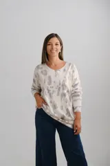 Sweter de punto amplio con escote en V y mangas largas, con estampado abstracto en tonos verdes, grises y detalles dorados.