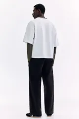 Pantalón en mezcla de algodón color negro, con cintura elástica con cordón de ajuste y botón. Presenta bolsillos laterales discretos y costuras giradas en las piernas, con un corte relajado.