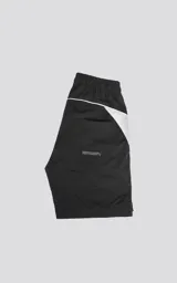 Bermuda negra de textil liviano con calce oversize, cintura elástica con cordón de ajuste y recortes decorativos en blanco. Presenta detalles reflectantes en los bolsillos delanteros y ribetes curvos blancos en la parte inferior.