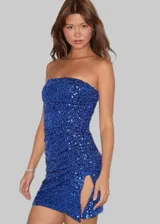 Vestido corto strapless de corte ajustado, confeccionado completamente en lentejuelas color azul vibrante. Presenta un diseño entallado con detalle de fruncido lateral y una abertura en el ruedo.