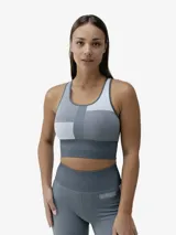Top deportivo de entrenamiento con diseño bicolor en tonos gris y blanco, confeccionado con tecnología seamless 3D y tejido Fit_Tech de efecto moldeador. Presenta un corte crop con escote redondo, espalda estilo nadadora y una banda elástica ancha en la base para mayor soporte.