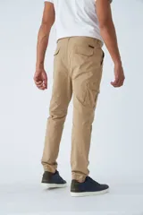 Pantalón cargo de hombre con fit slim, confeccionado en una mezcla de algodón y elastano. Presenta cierre de cremallera y botón, bolsillos laterales tipo cargo, pasa cinto y terminación con puños elásticos en los tobillos.