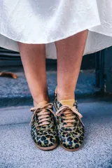 Zapatillas de estilo running con estampado animal print de leopardo. Presentan detalles en color ocre en la lengüeta, cordones, collarín y talón. Cuentan con una suela de goma dentada, entresuela blanca y una cuña interna oculta para mayor comodidad.