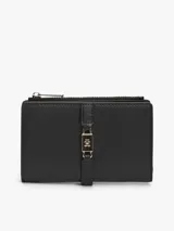 Billetera bifold de Tommy Hilfiger en color negro, confeccionada en poliuretano con acabado texturizado. Presenta un cierre principal con cremallera y una solapa frontal con un detalle metálico distintivo de la marca con el logo TH.