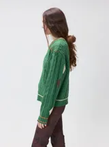 Sweater de punto con diseño de ochos en color verde, cuello redondo con detalle de franja en contraste, y apliques de rombos en las mangas. Presenta un bordado con la letra M en el pecho.