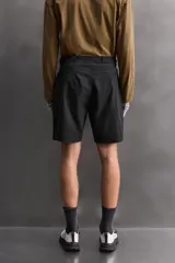 Bermuda de ajuste regular color marrón oscuro, confeccionada en tejido técnico compacto con elasticidad. Presenta cintura ajustable con cinturón negro a contraste, bolsillos frontales y un bolsillo cargo con cierre de cremallera oculta en la pernera.