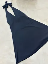 Vestido corto negro con escote halter atado al cuello.