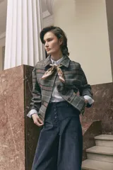 Tapado corto de lana con diseño a cuadros en tonos grises, marrones y azules. Presenta cuello camisero, cierre frontal con botones y mangas largas.