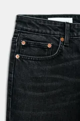 Jeans de denim azul oscuro con efecto desgastado y lavado, tiro bajo, corte bootcut y bajo flare. Presenta cinco bolsillos y cierre frontal con cremallera y botón.