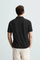 Polo de manga corta color verde oliva, con cuello solapa y abertura frontal tipo polo. Presenta una textura acanalada vertical y un calce regular.