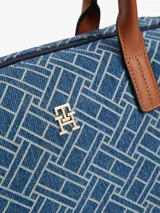 Cartera tote compacta Tommy Hilfiger de tejido denim con estampado geométrico integral del monograma TH, asas superiores en tono marrón y correa de hombro ajustable y extraíble. Cuenta con cierre de cremallera y herrajes dorados.