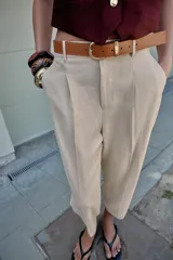 Pantalón tobillero azul marino de tiro medio, con pinzas delanteras, bolsillos frontales, falsos bolsillos con solapa en la espalda y cierre frontal con cremallera, botón y gancho. Incluye cinturón de cuero sintético tostado con hebilla metálica dorada.