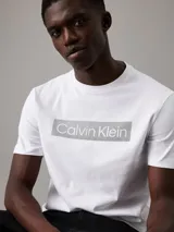 Remera blanca de algodón con cuello redondo y mangas cortas. Estampado frontal con el logo de Calvin Klein en un recuadro gris.
