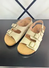 Sandalias color beige con doble tira sobre el empeine y hebillas doradas.