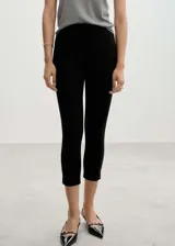 Calza capri negra de tiro alto con cintura elastizada, corte skinny y cierre lateral invisible.