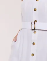 Vestido midi abotonado verde melange, con escote recto, tirantes anchos y falda de calce recto con vuelo sutil. Tiene abotonadura frontal completa con botones estilo carey, cinto textil con hebilla para ajustar la cintura y bolsillos laterales.