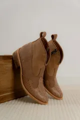 Botas cortas de estilo western confeccionadas en cuero, con puntera y talón texturizados con diseño de reptil y paneles laterales de gamuza. Presentan cierre lateral, tirador en la parte superior y taco bajo de madera.