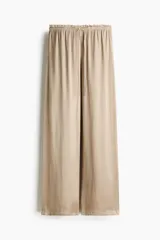 Pantalón fluido de satén color beige, de corte holgado y piernas amplias, con cintura elástica fruncida y cordón ajustable.