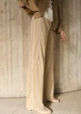 Pantalon de corte recto y tiro medio en color beige, con detalle de rayas laterales verticales en contraste blanco. Cuenta con cintura elástica y bolsillos laterales.