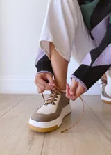 Championes de cuero color visón con cordones marrones, suela blanca y base color caramelo.