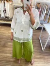 Blusa blanca de manga 3/4 con bordados en hilo verde oliva, cuello mao con abertura y botones, y terminación bordada en el ruedo y puños.