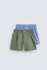 Pack de dos calzoncillos tipo bóxer de algodón en popelina, con cintura elástica y botones en la bragueta. Uno de los bóxers es de color celeste liso y el otro cuenta con estampado de cuadros en tonos verde y blanco.