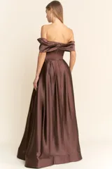 Vestido largo de fiesta confeccionado en satén color marrón chocolate. Presenta un diseño strapless con escote tipo solapa que cae sobre los hombros, cuerpo entallado y falda amplia con vuelo y bolsillos laterales.