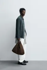 Bolso de hombro marrón con efecto serraje. Tiene un compartimento principal con cierre magnético y un bolsillo interior con cremallera. El asa es del mismo material.