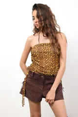 Falda de microtul estampado con lunares amarillos sobre fondo marrón, con fruncido lateral ajustable mediante cordones. Puede usarse como falda o como top.