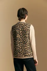 Chaleco de textura afelpada con estampado animal print, cuello redondo y cierre frontal con botones a presión. Cuenta con bolsillos laterales y ribetes al tono.