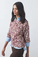 Sweater de punto con diseño de estampado animal print abstracto en tonos tierra y azul claro. Presenta cuello redondo a la base, mangas largas levemente amplias y terminaciones acanaladas en puños y ruedo.
