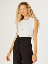 Camiseta sin mangas color blanco roto, con cuello redondo y hombros ligeramente caídos, de corte recto y ajustado al cuerpo.