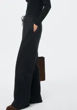 Pantalón de corte recto y holgado, color blanco, con cintura elástica y cordón ajustable. Presenta costuras verticales frontales que estilizan la silueta.